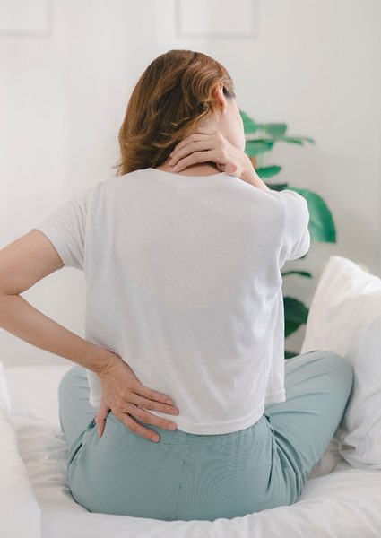 Woman sitting up in bed, experiencing aches and pains