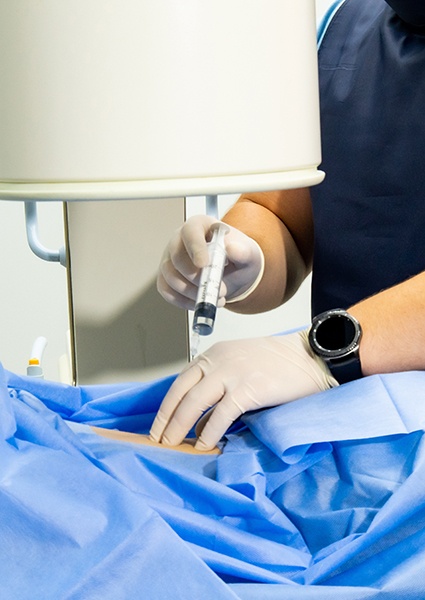 Medical professional placing injection in patient’s back