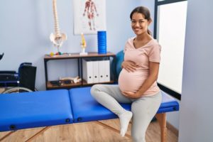 Pregnant woman sitting on table in doctor’s office